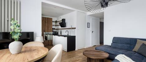 Una sala de estar moderna con una mesa de comedor de madera, un sofá azul y una lámpara de techo original.