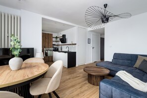 Appartement Deluxe, vue ville | Coin séjour | TV connectée de 50 pouces avec chaînes par câble, espaces bureaux
