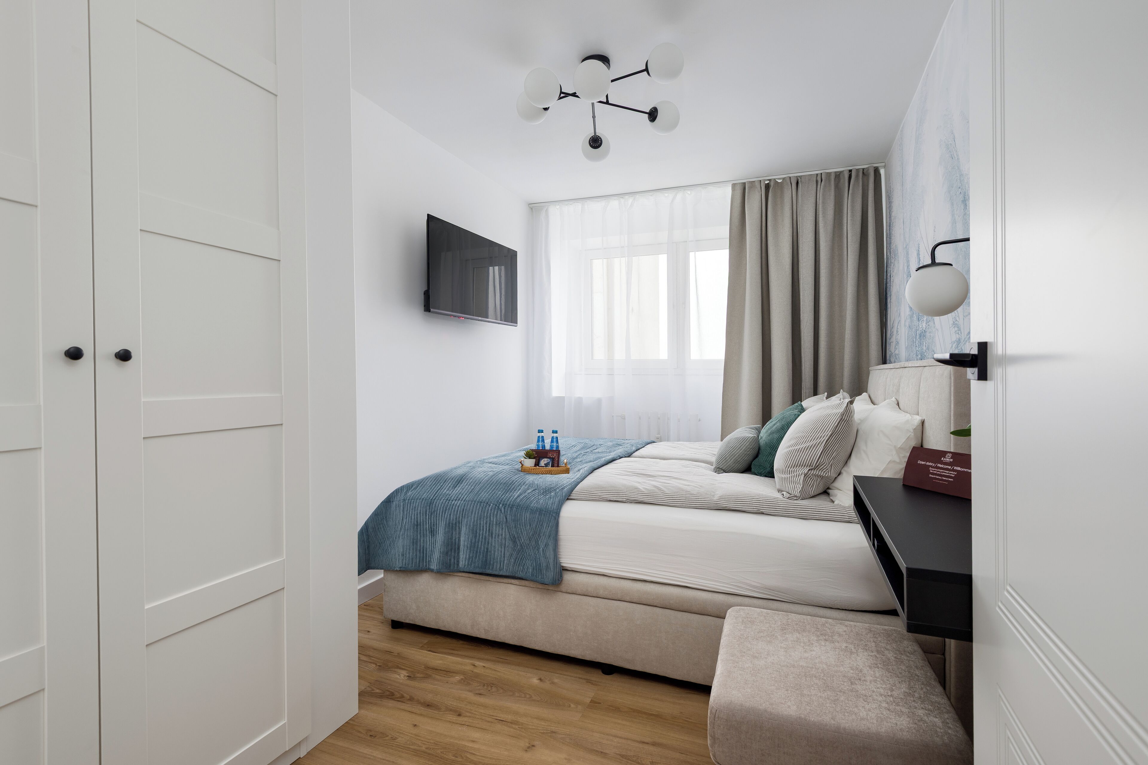 A bedroom with a bed, bedside table, TV, and a wardrobe.