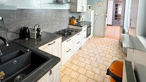 A compact kitchen with grey tiles, a black sink, a stove, and white cabinets. - 5 bedroom house and courtyard - 1930's Roubaix (Roubaix)