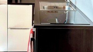 Een moderne keuken met een inbouwfornuis, een roestvrijstalen spoelbak en een enkel stopcontact.