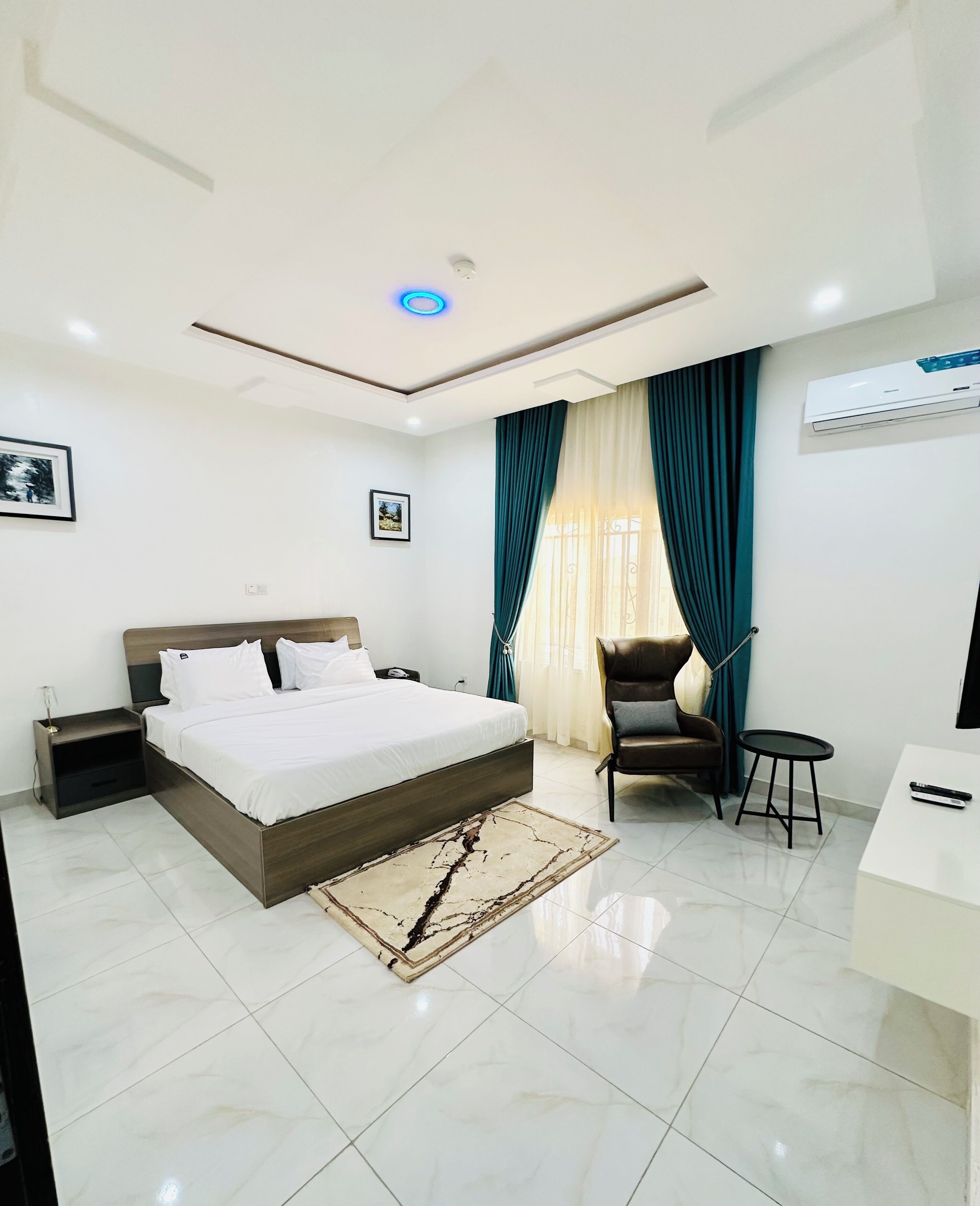 A modern bedroom with a large bed, a desk, a chair, and a small table.