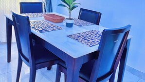 A dining table with four chairs, a potted plant, and a woven basket. - Urban Ts (Abuja)