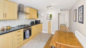 A modern kitchen with wooden cabinets, a gas stove, and a wooden dining table. - Host Stay The Coastal Retreat in Saltburn (Saltburn-by-the-Sea)