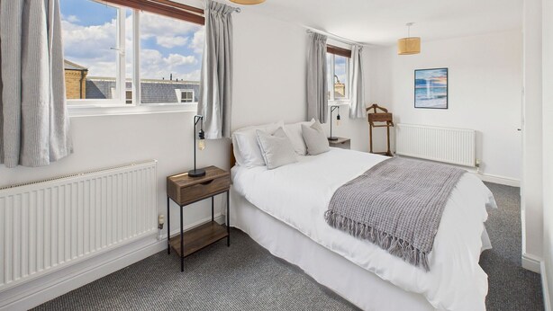 A bedroom with a large bed, two bedside tables, a radiator, and a window with curtains. - Host Stay The Coastal Retreat in Saltburn (Saltburn-by-the-Sea)