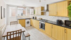 A compact kitchen with wooden cabinets, a built-in oven, and a sink. - Host Stay The Coastal Retreat in Saltburn (Saltburn-by-the-Sea)