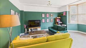 A living room with a green wall, a yellow sofa, a TV, and framed pictures. - Host Stay The Coastal Retreat in Saltburn (Saltburn-by-the-Sea)