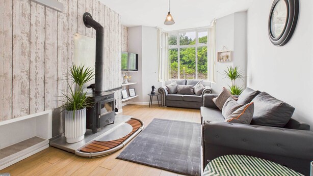 Una sala de estar acogedora con chimenea, un sofá y un ventanal con vistas a la vegetación.