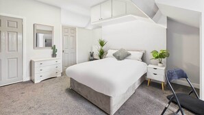 Un dormitorio con una cama grande, una mesita de noche, un aparador y una silla.