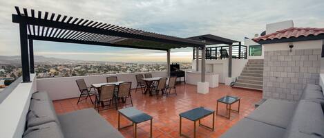 A rooftop terrace with outdoor seating, a piano, and a view of the cityscape.