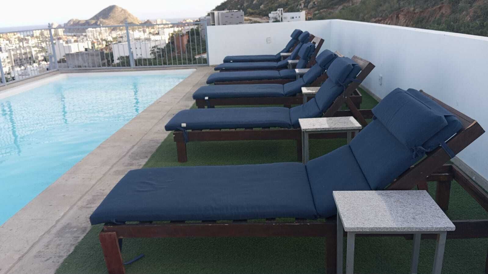 A rooftop pool area with lounge chairs and a view of the cityscape.