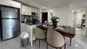 A modern kitchen with a stainless steel refrigerator, a microwave, and a sink. There is a dining table with chairs and a vase with flowers. - The Residences Apart-Hotel By Morgan (Cabo San Lucas)