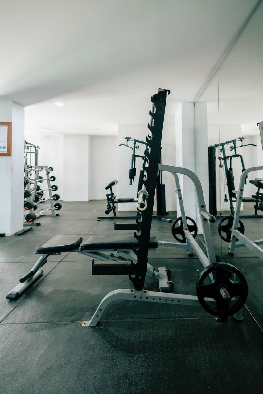 Une salle de sport équipée de divers appareils de musculation, notamment des bancs et des supports à squats.