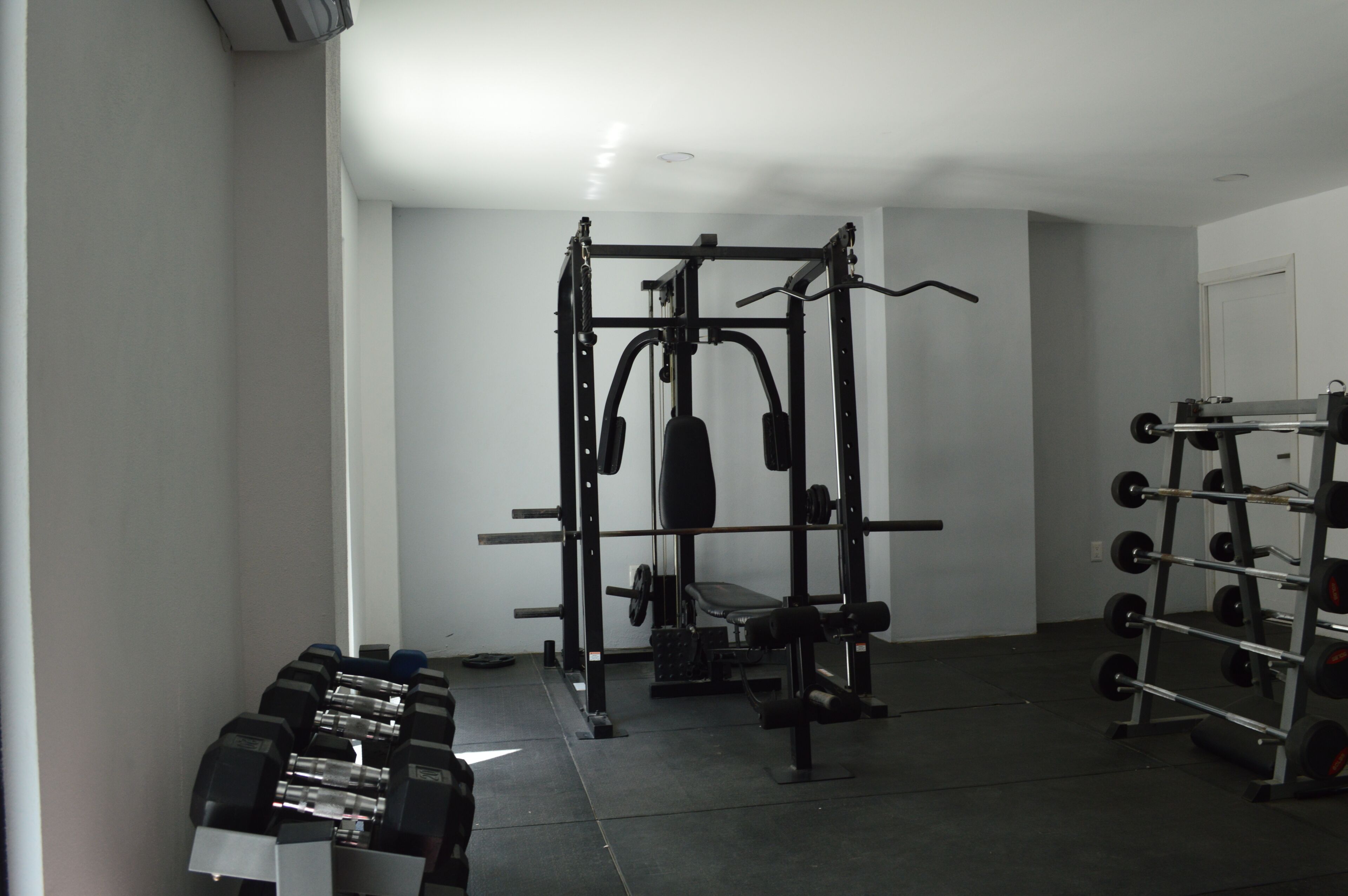A gym with weightlifting equipment, a bench, and dumbbells.