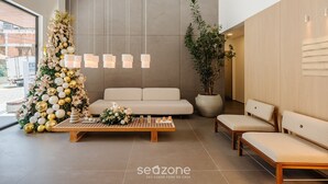 A modern interior with a large Christmas tree, a sofa, and a bench. - Apto Novo com 3 Suites a 600 m da Praia ELJ1201 (Itapema)