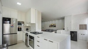 A modern kitchen with white cabinetry, stainless steel appliances, and a marble backsplash. - Apto Novo com 3 Suites a 600 m da Praia ELJ1201 (Itapema)