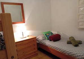 A bedroom with a wooden dresser, a bed with a patterned bedspread, a green pillow, and a red pillow. - Charming Farmhouse Retreat in Santa Ursula, Tenerife (Santa Ursula)