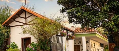 A two-story house with a tiled roof, a wooden door, and a gated entrance.