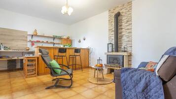 A cozy living room with a fireplace, a dining area with wooden furniture, and a kitchen with a stone accent wall.