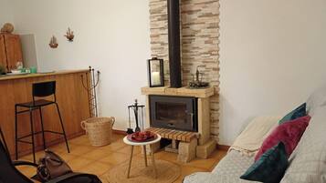 A cozy living area with a fireplace, a dining table with chairs, and a sofa with cushions.