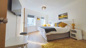 Ein Schlafzimmer mit einem Bett, Nachttischen, einem Fernseher und einem Fenster.