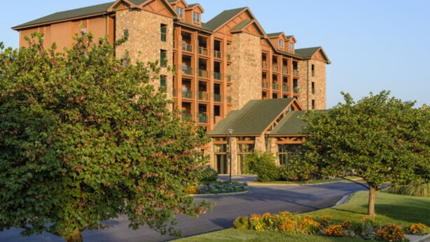 A multi-story hotel with a stone facade, multiple balconies, and a well-maintained lawn with trees and flowers. - DEC 27-Jan 3   89 per ngt.  COZY KING STUDIO! Enjoy Christmas Shows  in Branson (Branson)