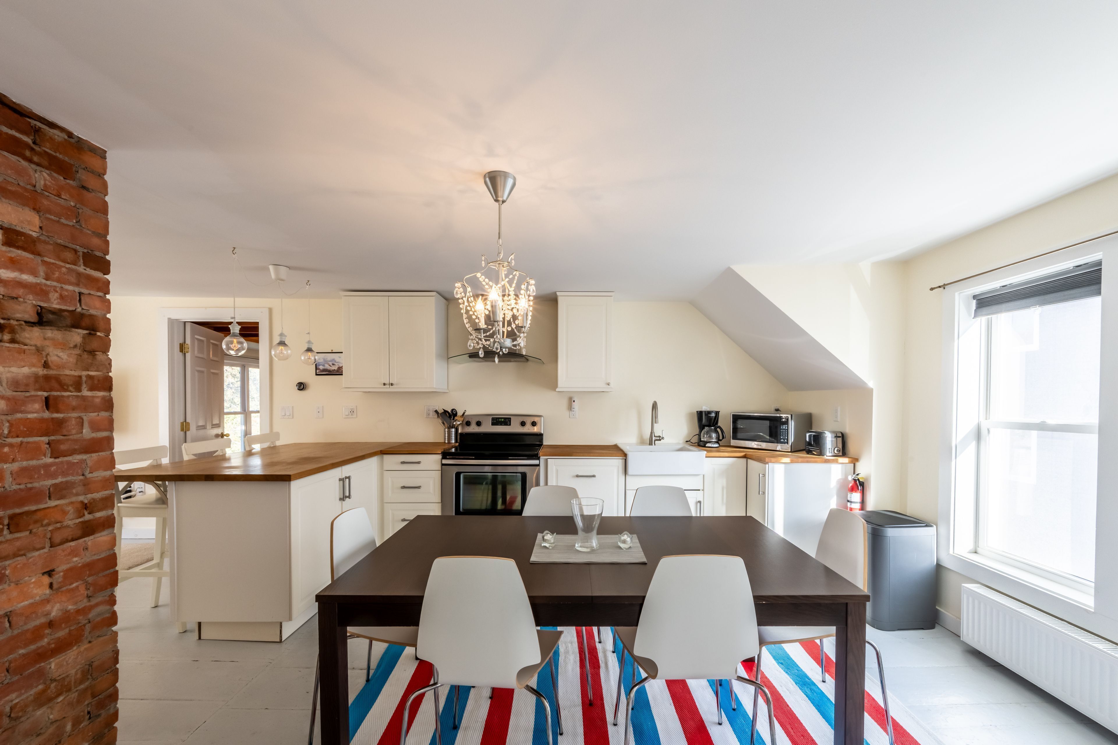 Una cucina moderna con mobili bianchi, un'isola centrale e un lampadario.