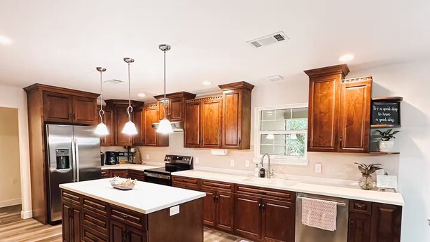 Una cocina moderna con armarios de madera, electrodomésticos de acero inoxidable e iluminación colgante.