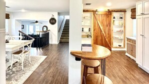 Un salón espacioso con piso de madera, una mesa de comedor con sillas y una escalera que sube a otro nivel.