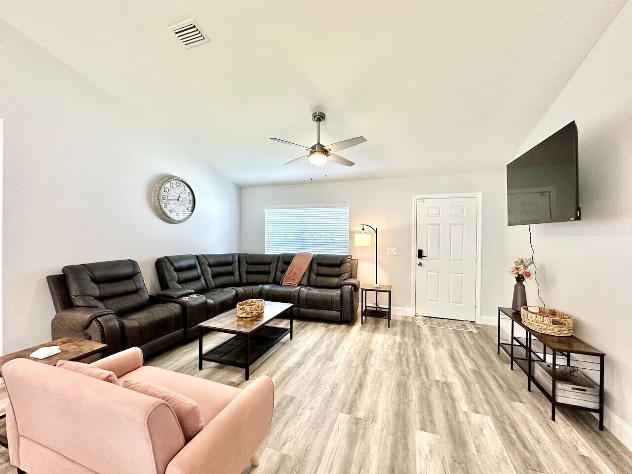 A modern living room with a sectional sofa, a coffee table, and a TV mounted on the wall.