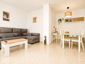 Ein modernes Wohnzimmer mit einer Couch, einem Couchtisch und einem Essbereich mit Stühlen und einem Tisch.