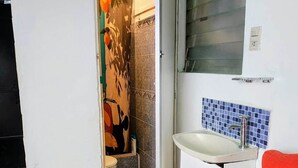 Een badkamer met douche, toilet en wastafel.
