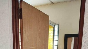 A narrow bathroom with a wooden door, a white sink, and a mirror above it. - Lombardia Planes de Renderos - Casa de Piedra (San Salvador)