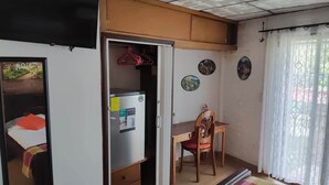 A room with a bed, a desk, a chair, and a wardrobe. There are pictures on the wall and a window with curtains. - Lombardia Planes de Renderos - Casa de Piedra (San Salvador)