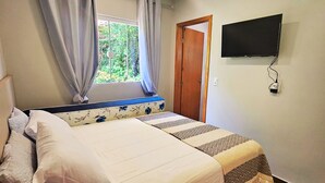 Ein Schlafzimmer mit Bett, Vorhängen, einem Fernseher und einem Fenster.