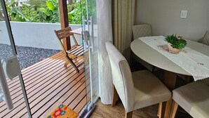 Ein Zimmer mit einer Glastür, die auf eine Holzdiele führt, einem runden Tisch mit Stühlen und einem kleinen Topfpflanzen auf dem Tisch.