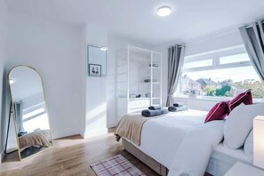 Een slaapkamer met een bed, een kledingkast, een spiegel en een raam met uitzicht.
