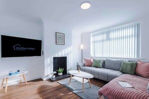 Een moderne woonkamer met een flatscreen televisie, een bank, een salontafel en een open haard.