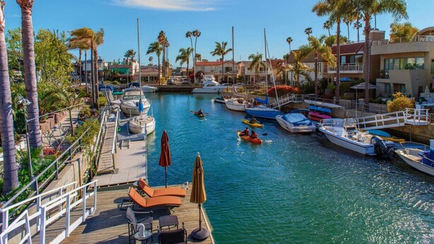 Un puerto deportivo con barcos amarrados, un muelle de madera con sillas de descanso y palmeras.