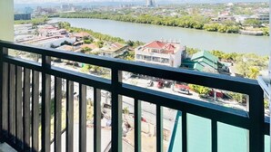 Un balcon offrant une vue sur une rivière, des bâtiments et des montagnes au loin.