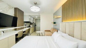 Une chambre d’hôtel comprenant un lit, une télévision, une kitchenette et un coin salon.