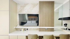 Une chambre d’hôtel moderne avec un mur en marbre, un grand miroir, un lit avec une tête de lit et un bureau avec des chaises.