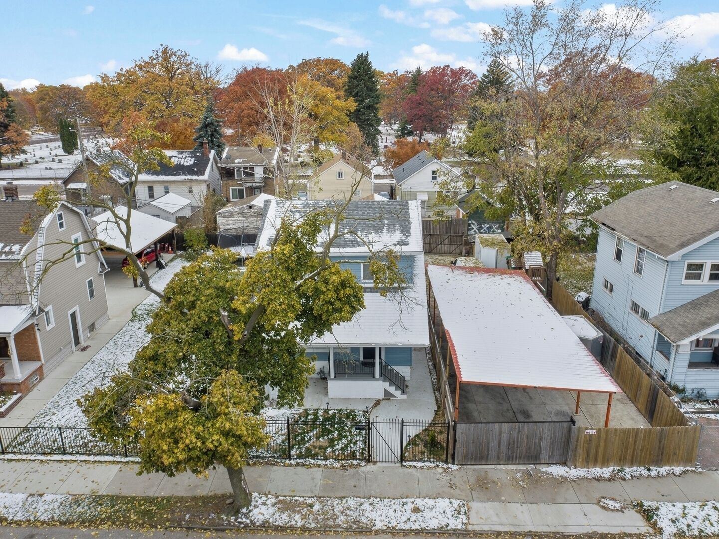 A residential area with houses, a tree, and a fenced yard.