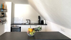A kitchen with a black countertop, a fruit bowl, a coffee machine, and a window. - Modern feel-good apartment in the Illertal (Dettingen an der Iller)