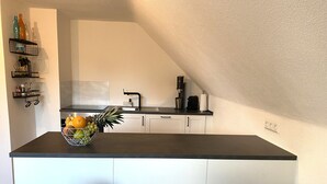 A modern kitchen with a dark countertop, white cabinets, and a built-in coffee maker. - Modern feel-good apartment in the Illertal (Dettingen an der Iller)