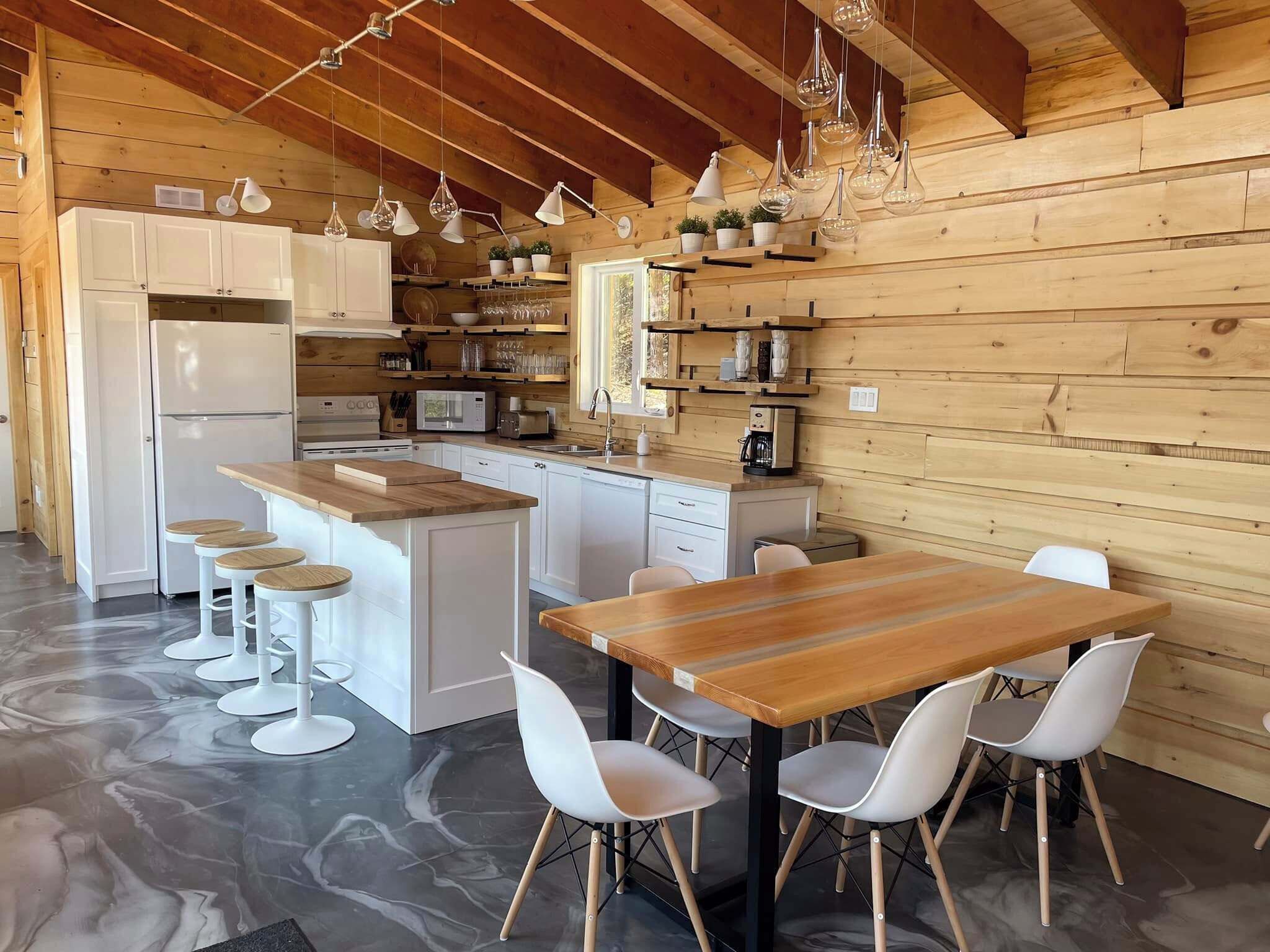 A modern kitchen with white cabinets, a central island with stools, and pendant lighting.