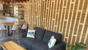A modern living area with a grey sofa, wooden coffee table, and a potted plant. - Chalet L'Orée Étoilée (La Bostonnais)