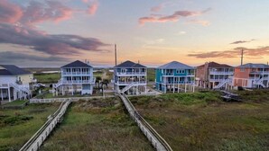 A coastal residential area with houses connected by a wooden boardwalk. - Beachfront | 4BR | Sleeps 14 | Pet-Friendly | NEW Hot Tub (Galveston)