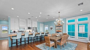 A spacious kitchen with white cabinets, a wooden dining table, and a chandelier. - Beachfront | 4BR | Sleeps 14 | Pet-Friendly | NEW Hot Tub (Galveston)