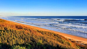 A beach with waves, a clear sky, and a forested area. - Retro Dunes - Wi-Fi. Linens. Fireplace. Pets OK (Venus Bay)